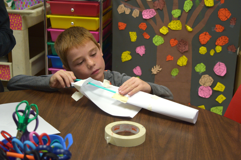 Student crafting with paper and straw